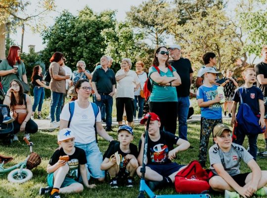 A diverse group of people enjoying a sunny day at an outdoor community event in a park setting.